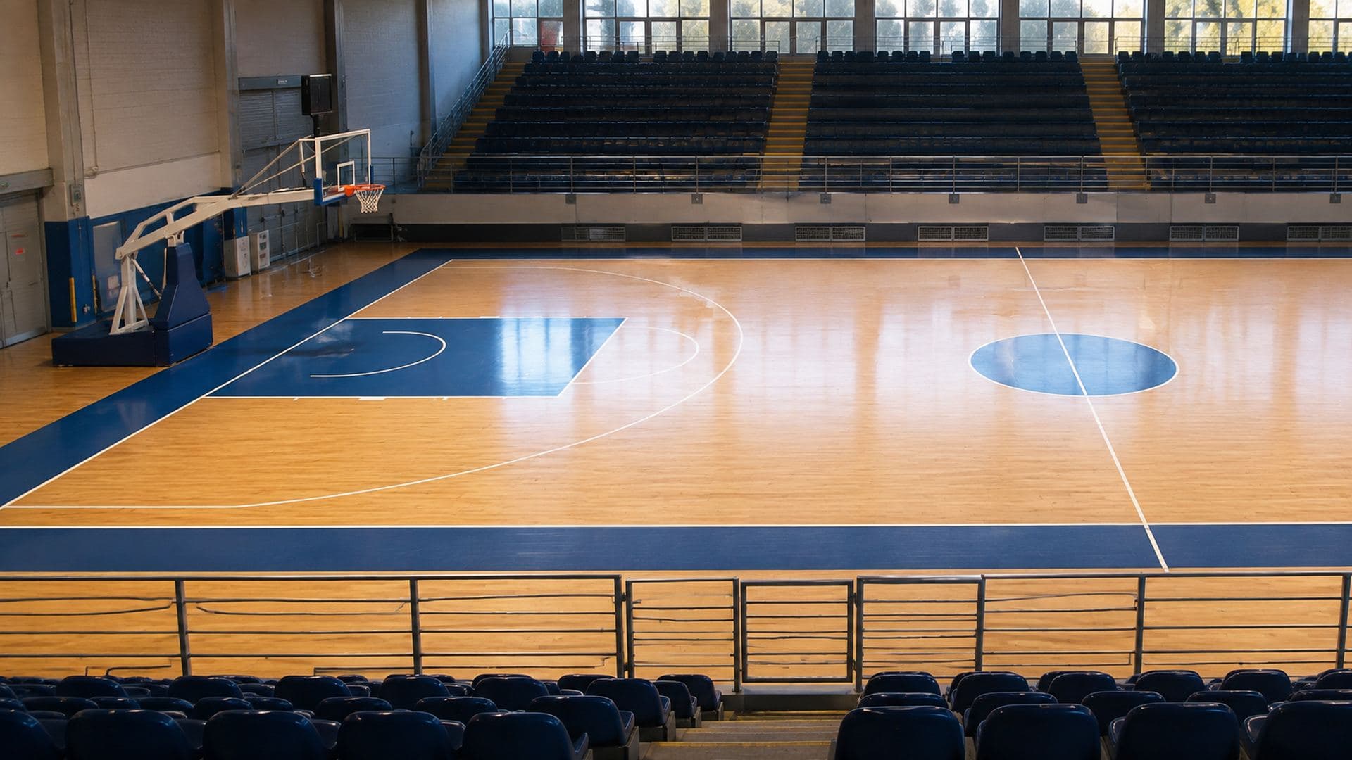 Empty basketball court seen from the stands, with the three-point line and the key clearly visible
